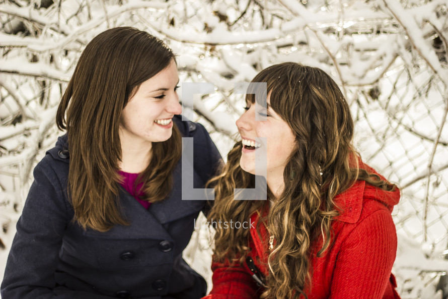 friends in winter coats talking and laughing 