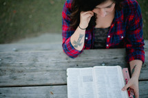 A woman reading a Bible outdoors. 