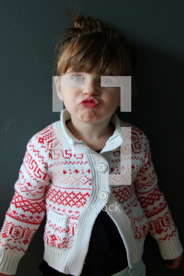 toddler girl standing in front of a chalkboard making a silly face 