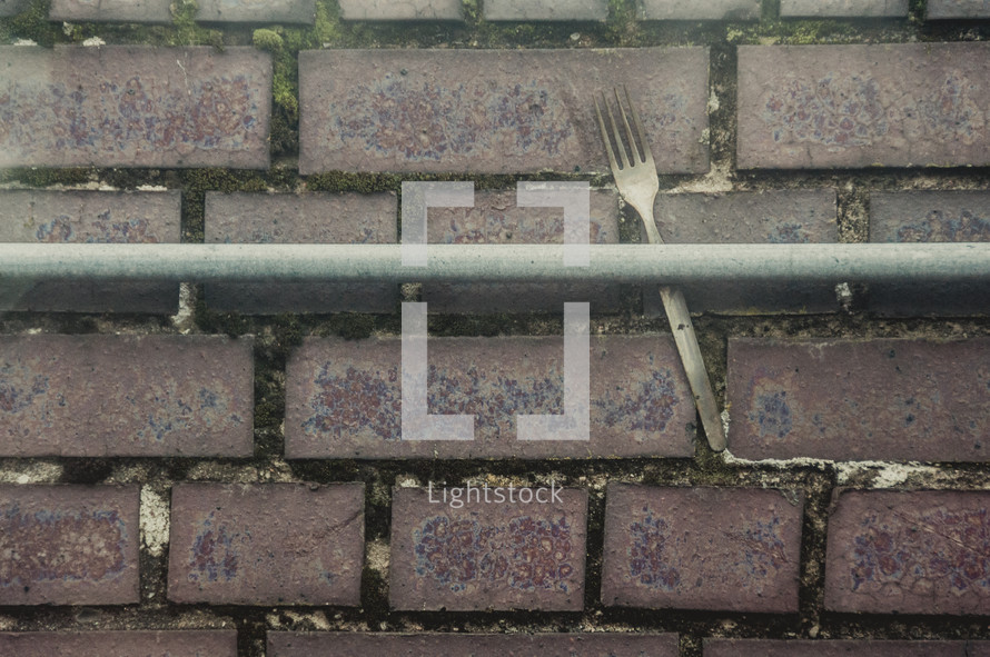 fork in a railing against a brick wall 