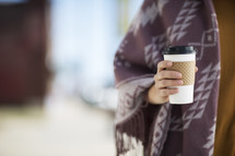 a woman in a shawl holding a coffee cup 