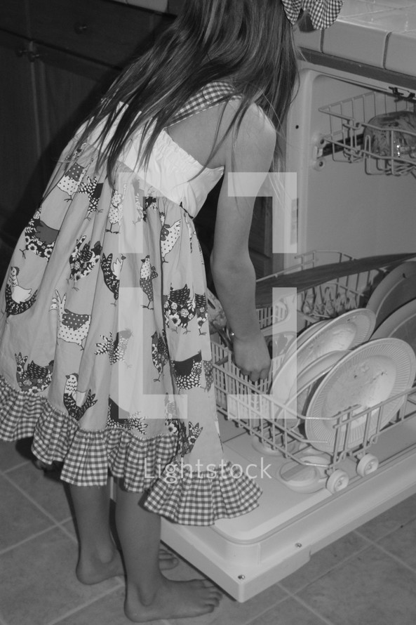 a little girl loading the dishwasher 