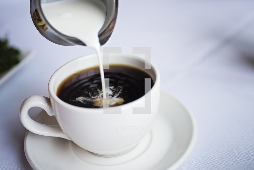 pouring creamer in coffee 