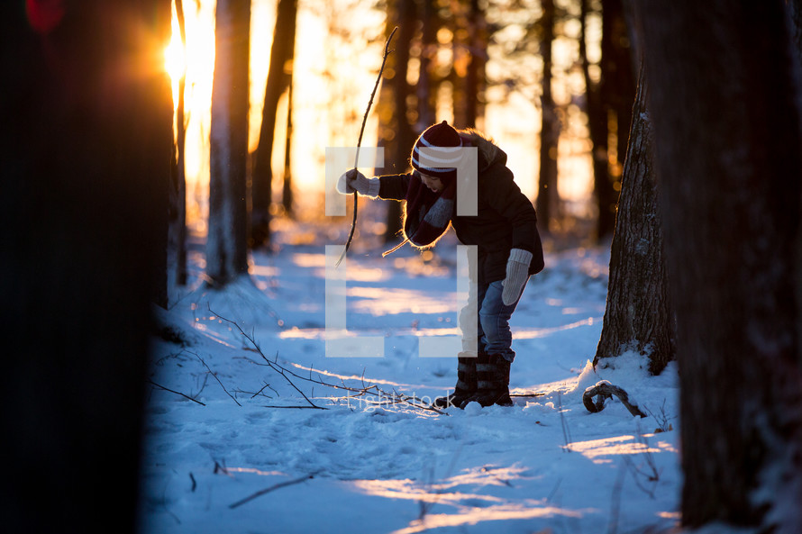 a child playing in snow in a forest 