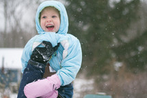 a girl child playing outdoors in the snow 
