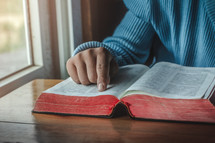 a person reading a Bible in a window 