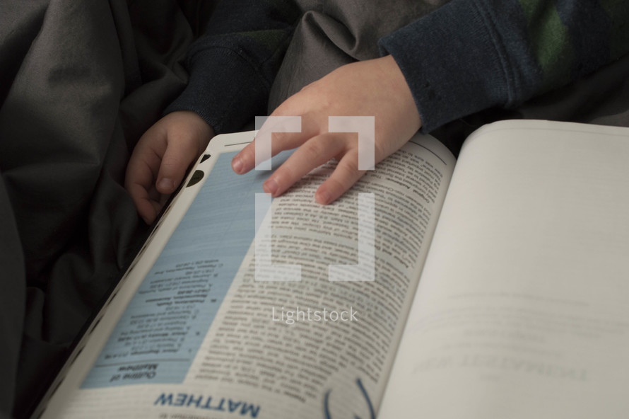 a toddler flipping through the pages of a Bible 