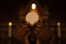 Close up of hands holding up a communion wafer. 