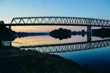 reflection of a bridge over water at dusk 