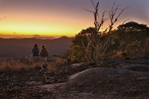 people sitting on a mountaintop watching the sunrise 