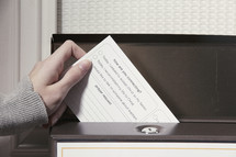 Hand placing a card in a box on a door.