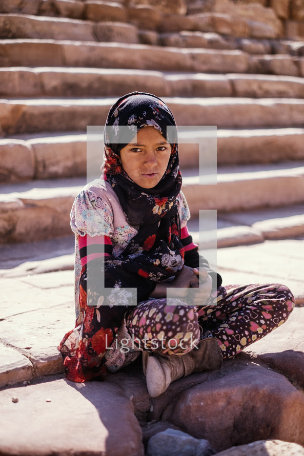 young girl sitting outdoors 