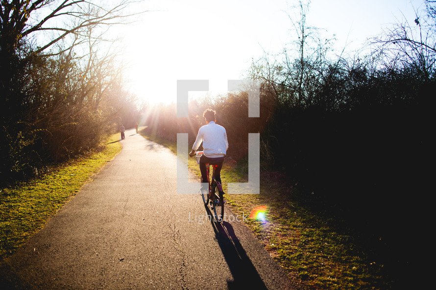 man riding a bicycle on a sunny path 