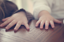 Children's hands on a wooden table.