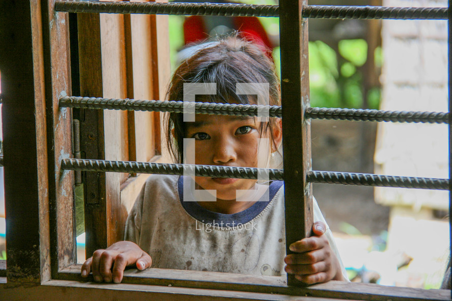 little girl looking through a window in Cambodia 