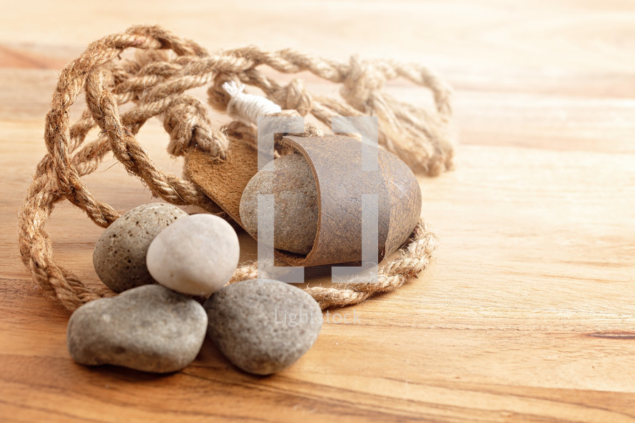 A Sling Shot and Stones on a Wooden Table from the Story of David and Goliath in the BIble 