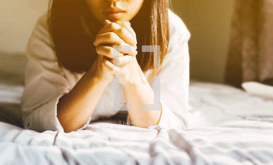 a woman praying in bed 