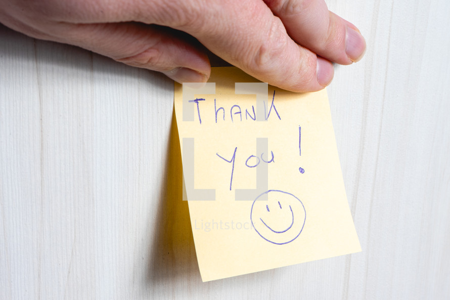 A sticky note hanging on the wall, with the text Thank You on it.