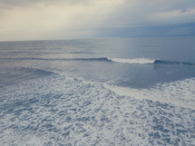 Drone image of the ocean while a wave is crashing.