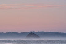 distant island under a pink sky at sunset 
