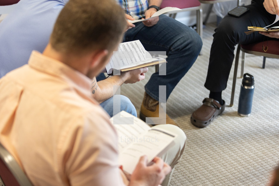 Selective focus on discussion questions in man's hands during men's Bible study during Sunday school at church, young men, young adults, young professionals