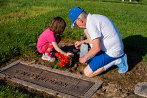 a granddaughter and grandfather spending time at a cemetery 