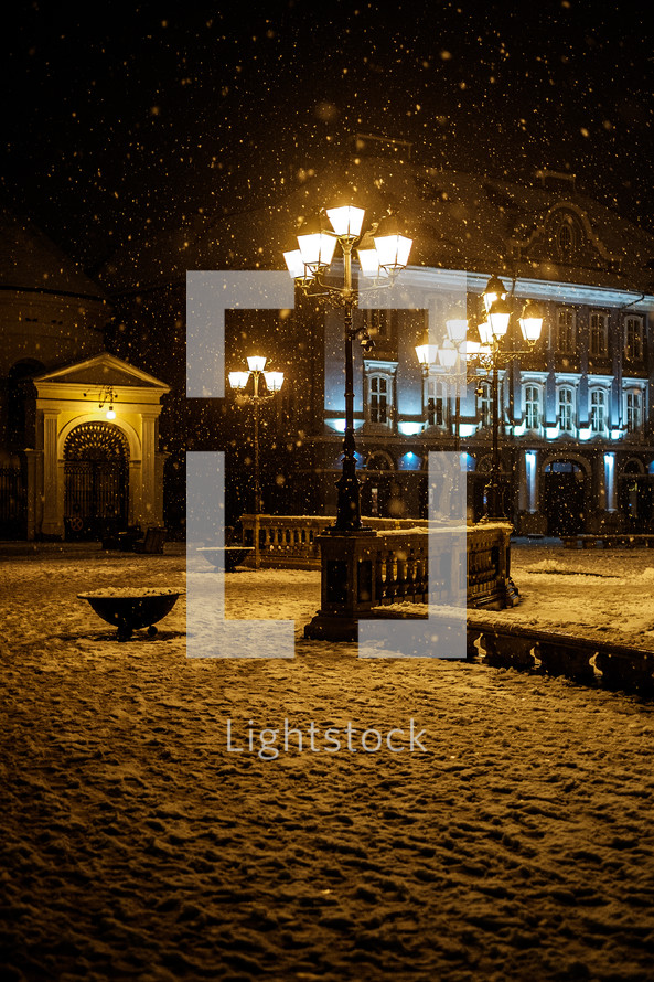 falling snow and street lamps in a city 