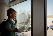 a child looking out a window at an airport 