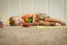 a toddler boy resting on the floor 