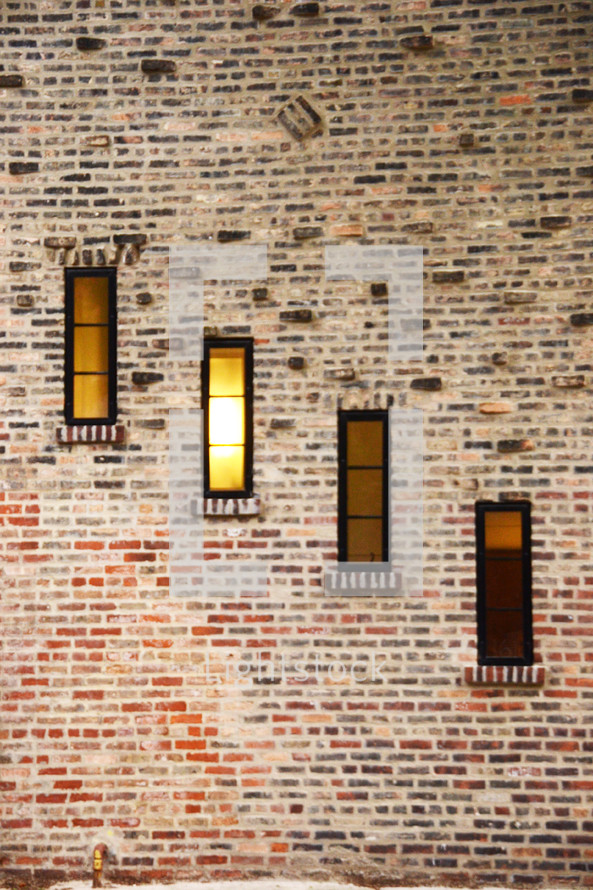A brick wall with four narrow rectangular windows.