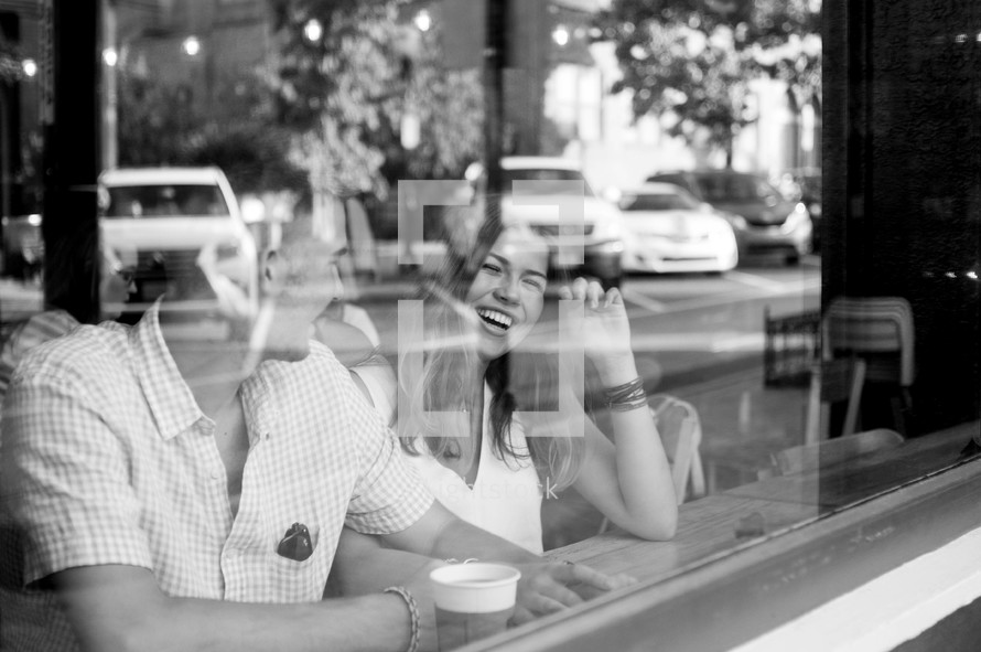 a couple sitting in the window of a coffee shop 