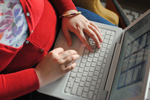 a woman typing with a laptop on her lap 