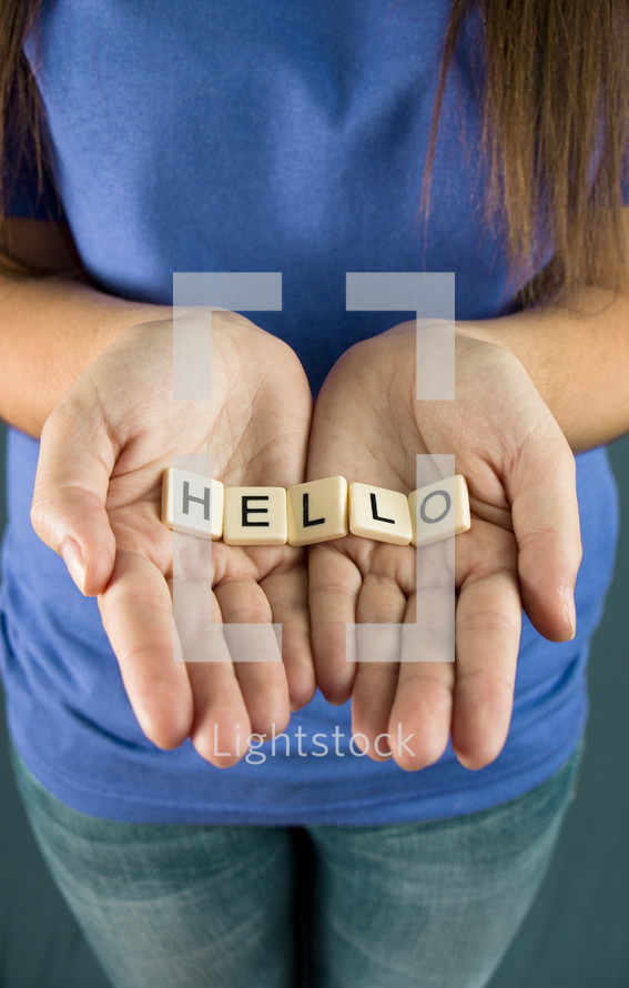 A girl holds out the word "HELLO"