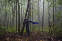 man hanging a hammock in a forest 