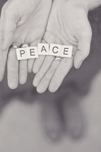 word peace in scrabbles pieces in a woman's hands 