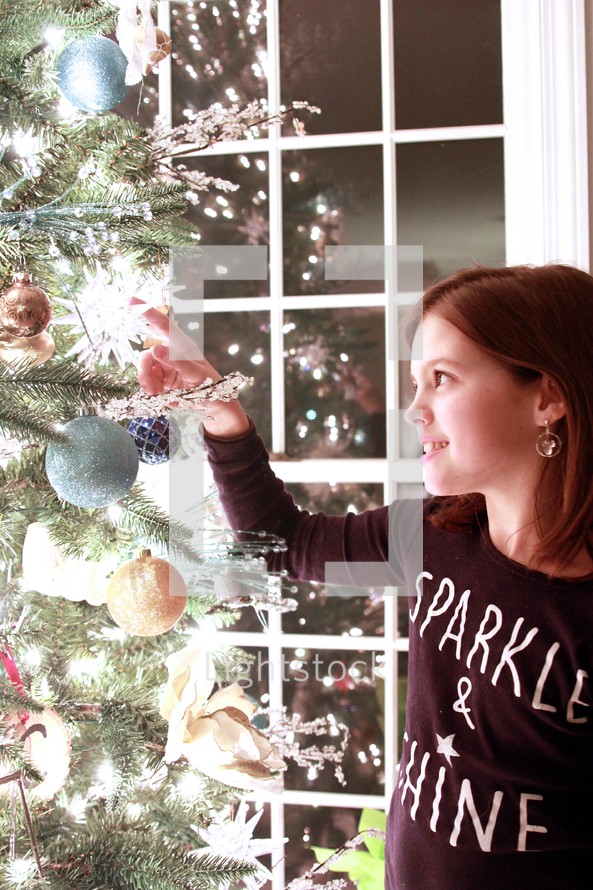 a child hanging an ornament on a Christmas tree 
