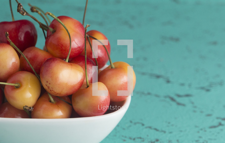 Sweet and Beautiful Red and Yellow Golden Cherries on a teal Background