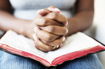 African-American in prayer with a Bible in her lap.