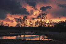 Sunset clouds over a watery field.