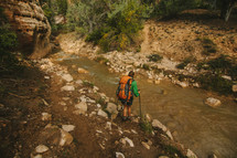 a woman backpacking along a stream 