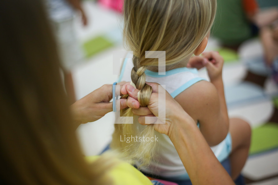 a woman braiding a girls hair 