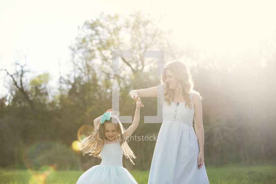 mother and daughter dancing under sunlight 