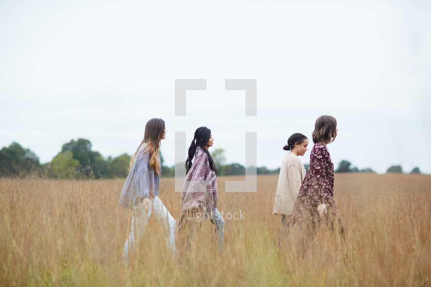 women walking through a field of tall grasses 