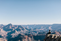 man sitting at the edge of a canyon cliff 