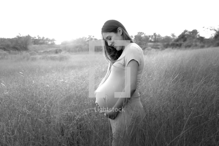 a pregnant mother standing in a field 