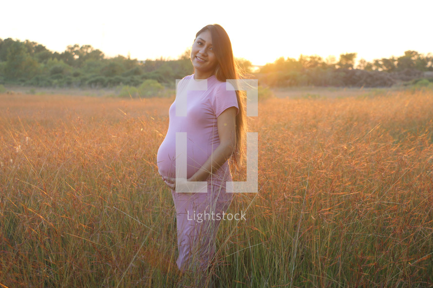 a pregnant woman standing in a field 