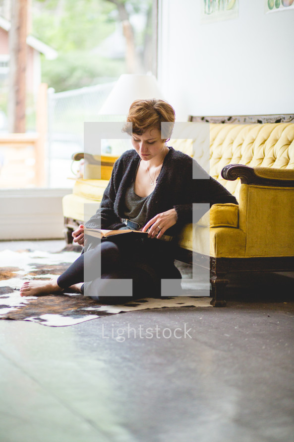 a woman sitting on the floor reading 