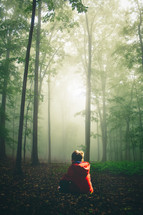 a boy sitting alone in a forest 