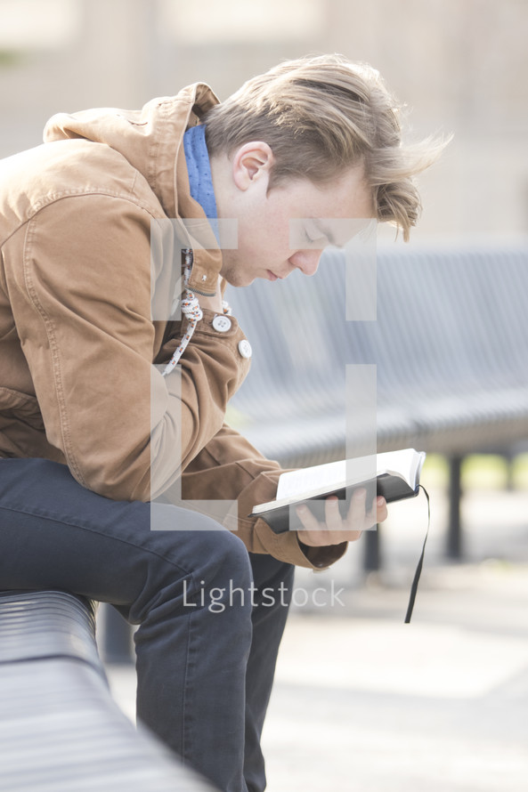 a man sitting on a bench reading a Bible 