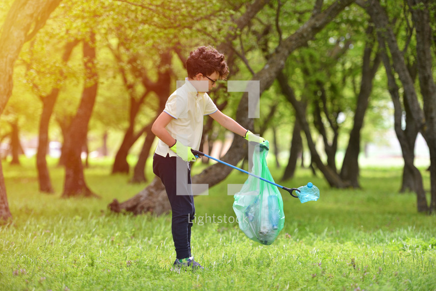 a young boy picking up trash outdoors 